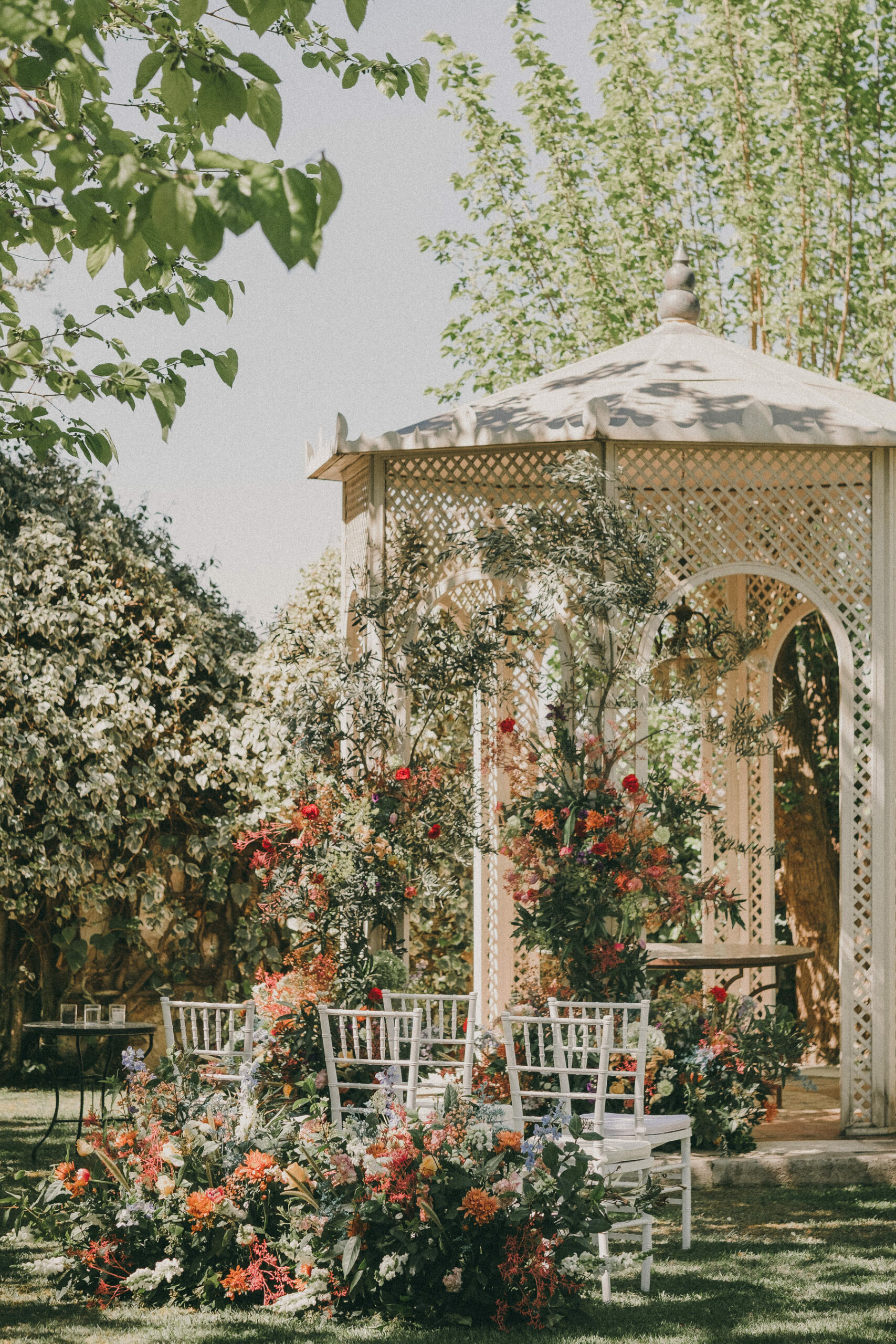 Quiosco blanco decorado con muchas flores que sobresalen. Es el escenario de una ceremonia civil al aire libre. Fotografía de boda por Love Wanderers. Wedding Planner Martin & Gutfreund