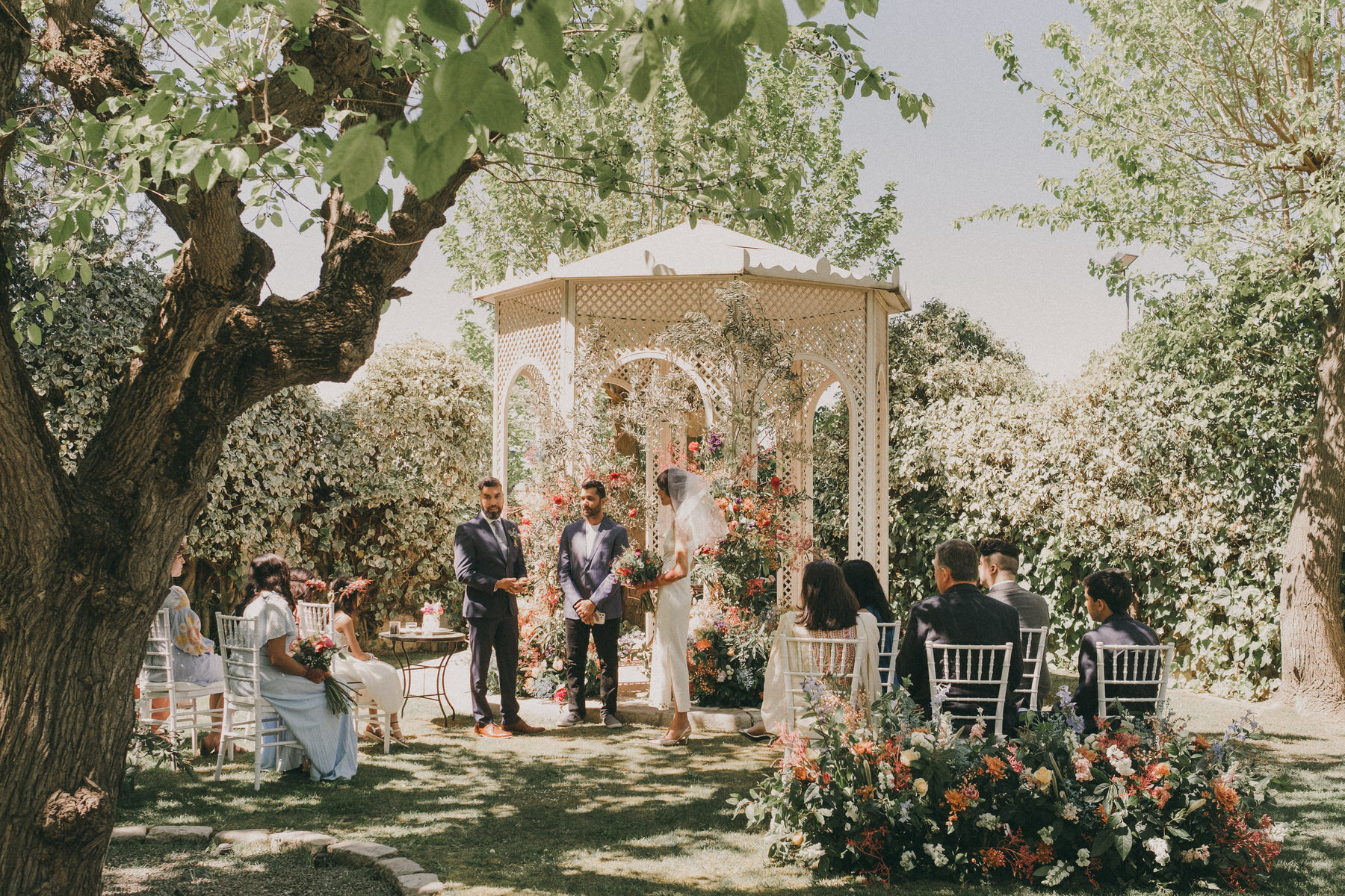 Ceremonia de boda civil que se lleva a cabo en un jardín frondoso en frente de un quiosco blanco y lleno de flores. Fotografía de boda por Love Wanderers. Wedding Planner Martin & Gutfreund